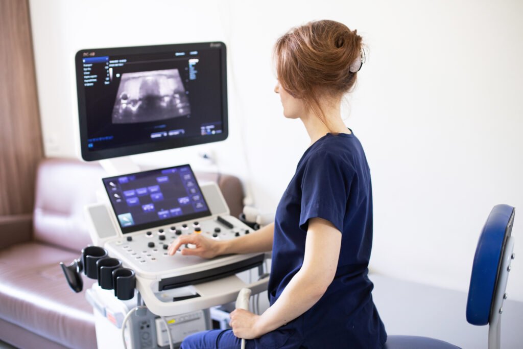 A professional female sonographer performing a pelvic ultrasound in Los Angeles inside a serene, modern medical clinic.